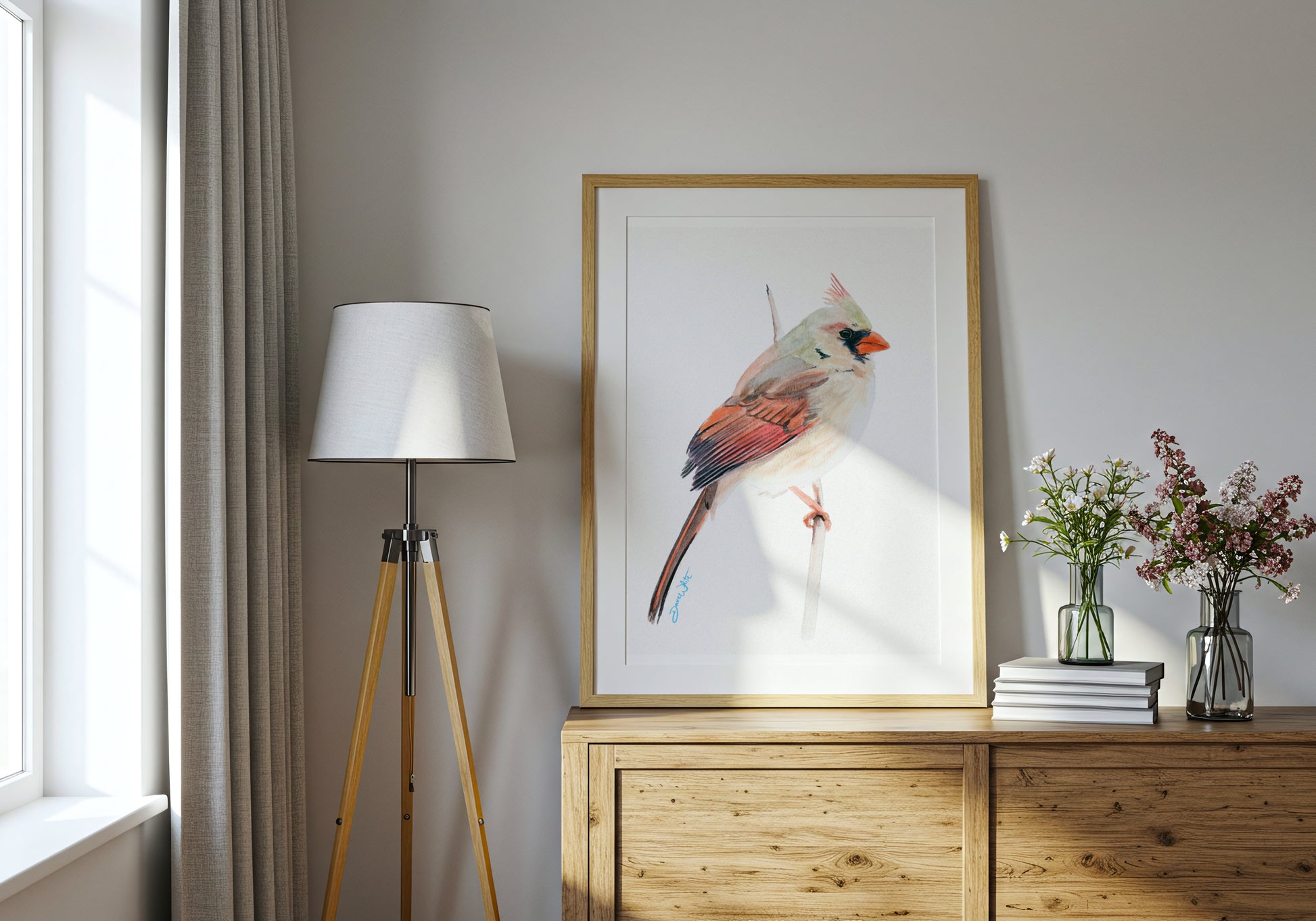 Framed cardinal bird artwork on a wall above a wooden cabinet with decor items.