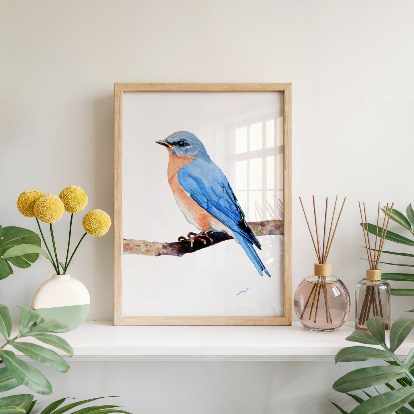 Framed artwork of a female blue bird on a shelf with decorative items and plants.