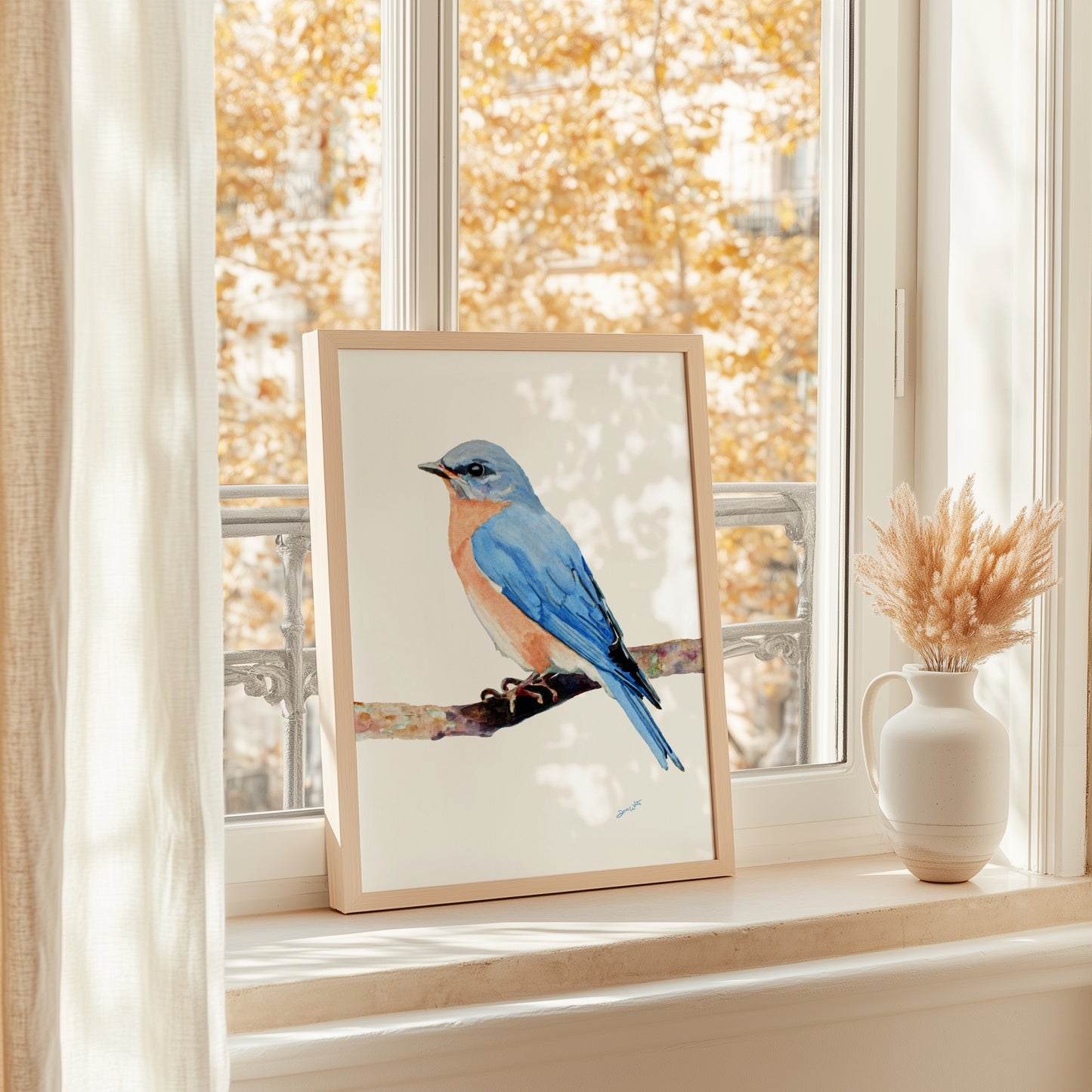 Framed artwork of a female blue bird on a windowsill with autumn foliage outside.