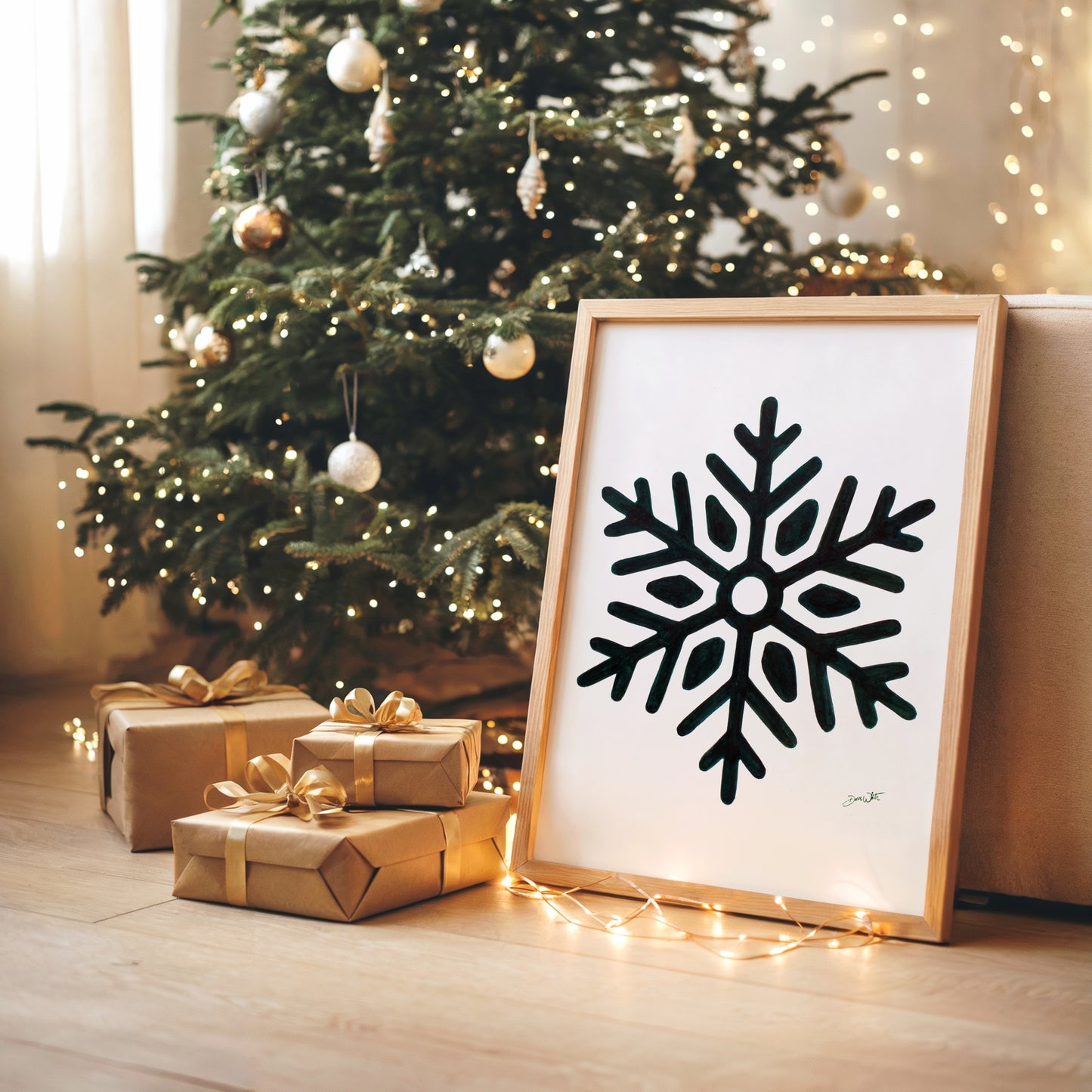 Framed forest green snowflake art on a wooden floor with a decorated Christmas tree in the background.