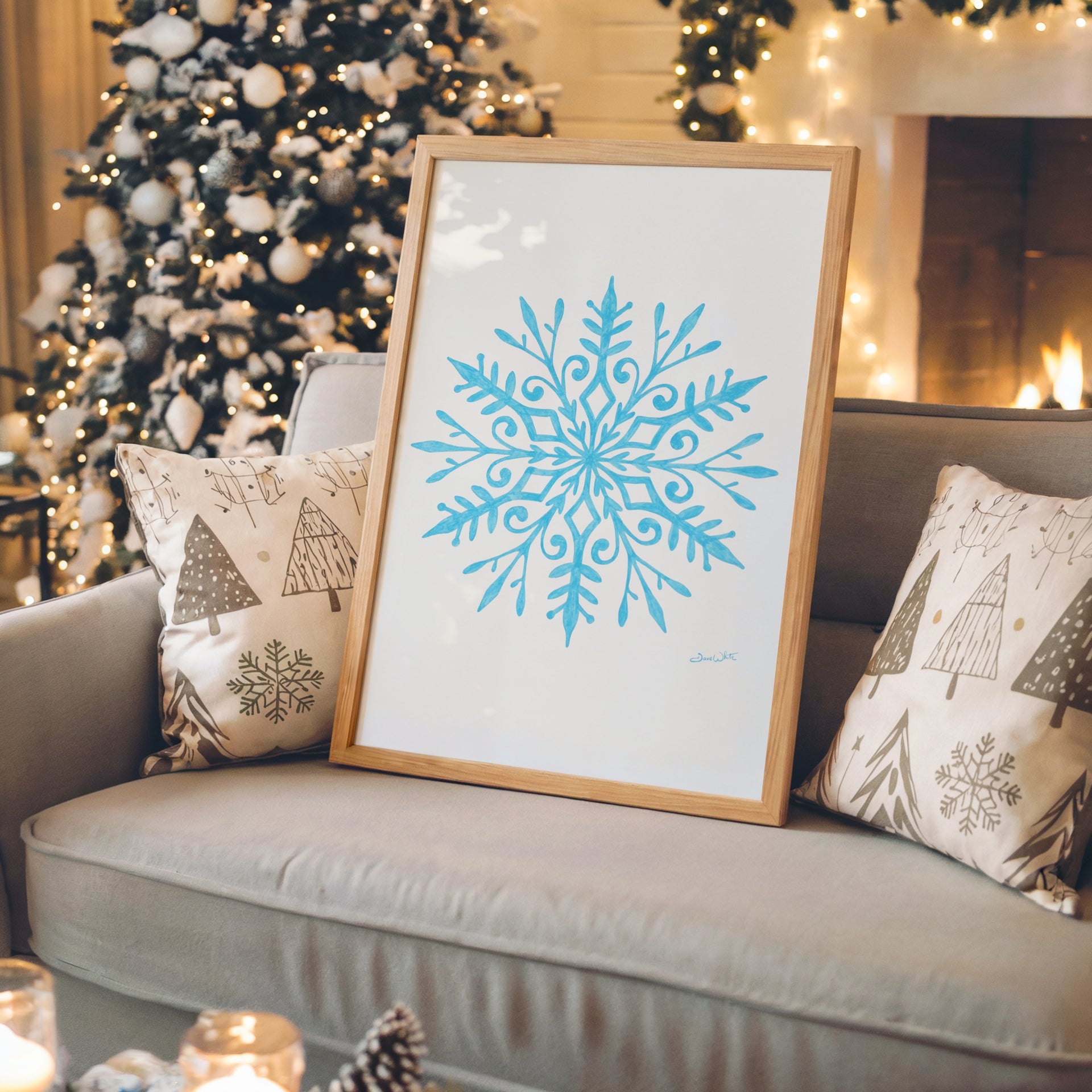 Framed blue snowflake print on a couch with Christmas decorations in the background