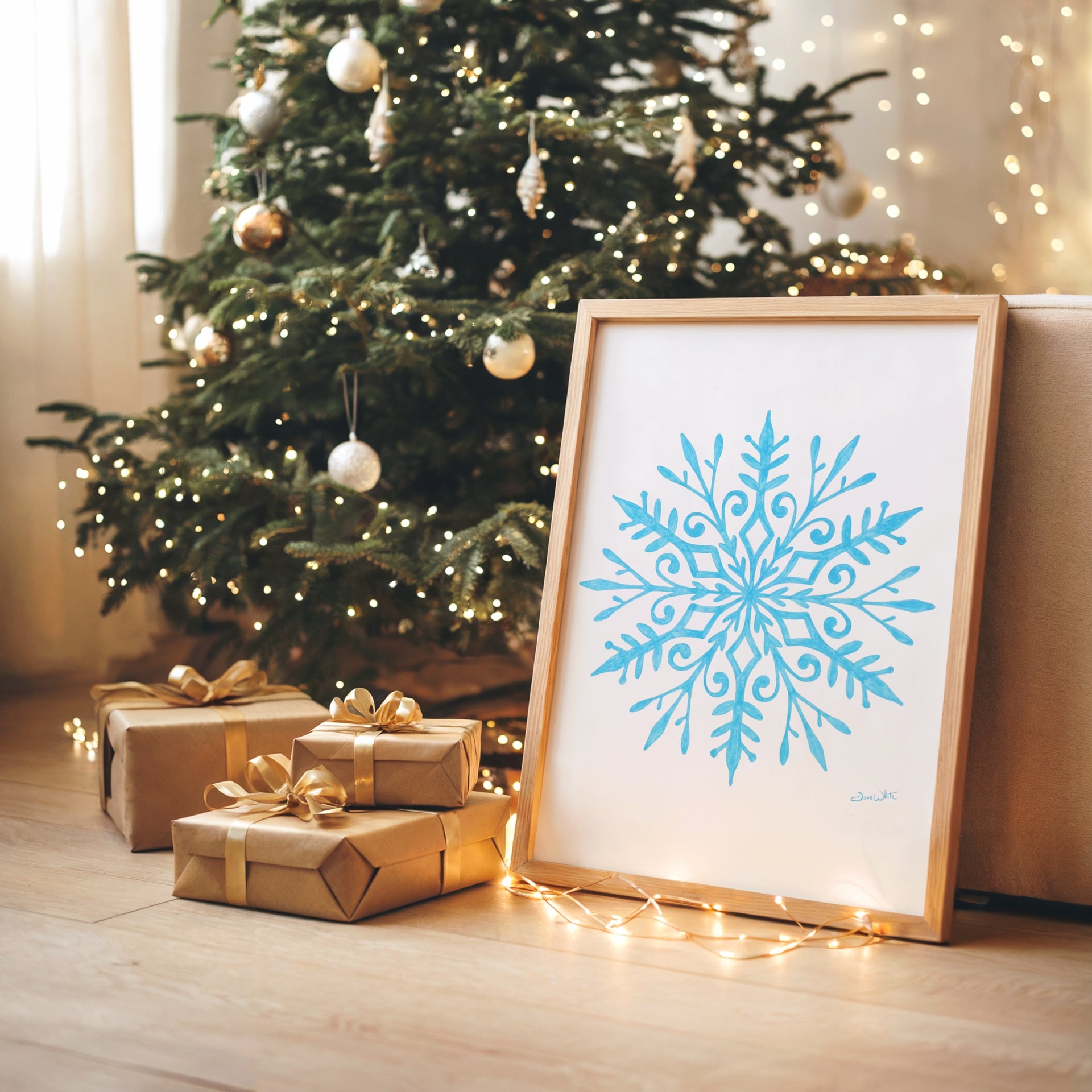 Framed snowflake art next to wrapped gifts and a decorated Christmas tree.
